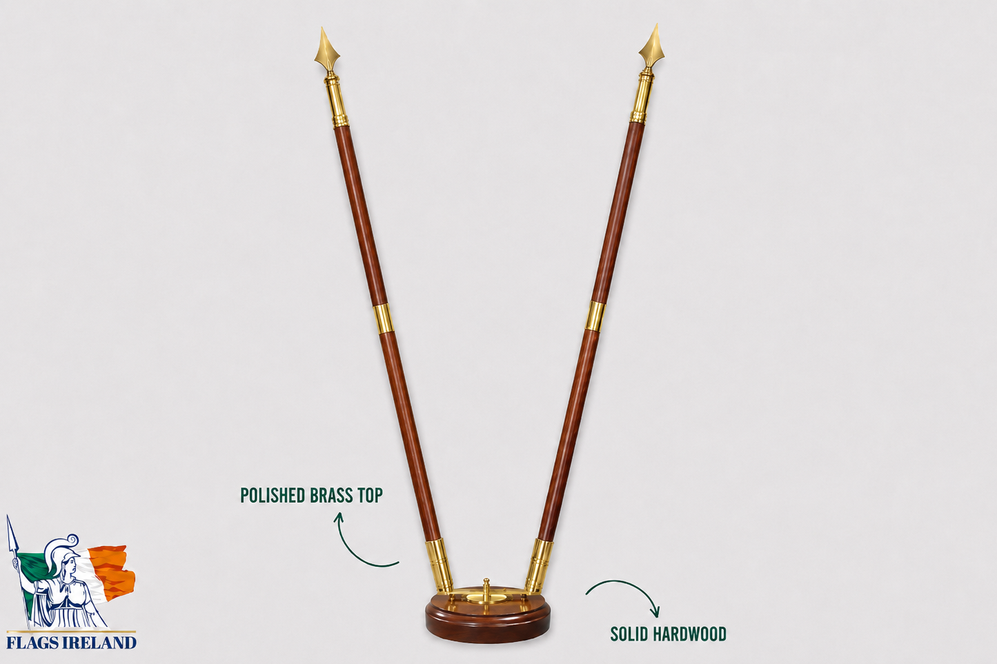 A polished brass and hardwood flagpole kit with a V-shaped base, shown on a light gray background with text callouts highlighting the polished brass top and solid hardwood construction. A 'Flags Ireland' logo is visible in the bottom-left corner.