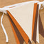 A handmade felt pennant banner with alternating cream, orange, and brown triangular flags tied to a white ribbon header, displayed on a wooden surface.