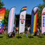 Colorful Pride feather banner flags on grass festival with people in the background