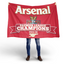 Person holding a red Arsenal flag with 'Premier League Champions 2025/26' text on a white background