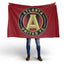 Person holding an Atlanta United FC flag on a white background