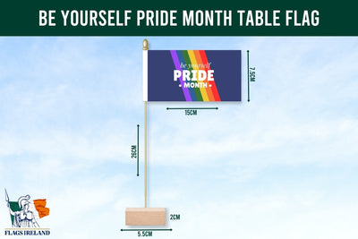 Pride month table flag with rainbow design and text on a blue background. Be Yourself Pride Month