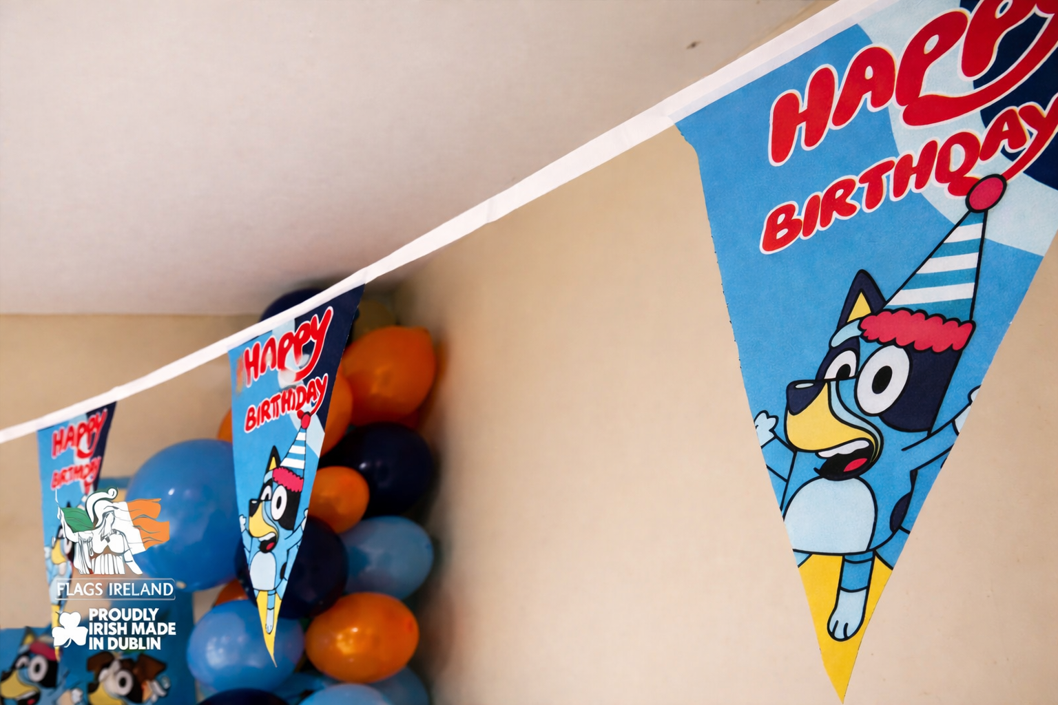 Birthday banner with cartoon character and 'Happy Birthday' text, hanging above colorful balloons.