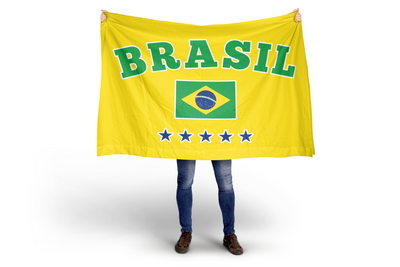 Person holding a large yellow flag with 'BRASIL' and the Brazilian flag design on a white background