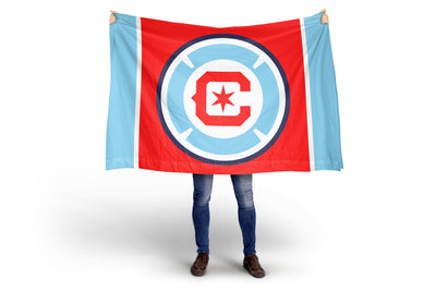 Person holding a Chicago FC red and blue flag with a logo on a white background