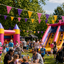 Children's party with inflatable slides and colorful bunting flags in a park.
