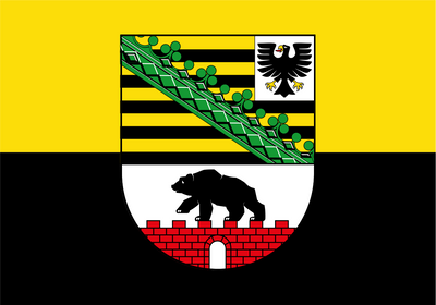 Saxony Anhalt Province Flag. The flag of Bamberg, Germany, featuring a horizontal bicolor design of yellow on top and black on the bottom, with a central coat of arms containing a green trellis, black-and-yellow stripes, a white eagle, a black bear, and a red brick wall.