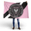 Person holding a flag with Club Internacional Inter Miami FC logo on a white background