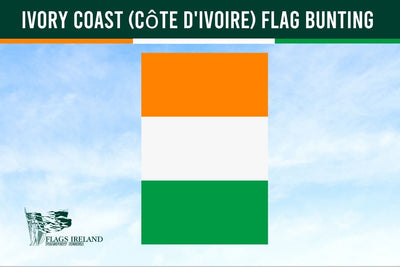 Ivory Coast flag bunting with a green header strip at the top, white text reading 'IVORY COAST (CÔTE D'IVOIRE) FLAG BUNTING,' and a vertical tricolor flag in orange, white, and green centered on a pale blue sky background. A small 'Flags Ireland' logo appears in the lower left.