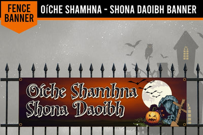 A Halloween-themed decorative banner displayed on a black metal fence. The banner has a dark red and orange gradient background with the text 'Oíche Shamhna Shona Daoibh' in white gothic lettering, accompanied by illustrations of a full moon, bats, a jack-o'-lantern, and a tombstone.