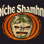 A graphic print featuring the Gaelic phrase 'Oíche Shamhna' in cream-colored stylized lettering above a central illustration of a shamrock mask with orange eyes, set against a circular orange and black background on a dark charcoal backdrop.