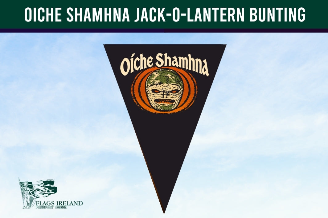 A triangular black pennant flag featuring the Oíche Shamhna mask emblem with orange and cream details, set against a light blue sky background. A dark green banner at the top reads 'OICHE SHAMHNA JACK-O-LANTERN BUNTING' and a 'Flags Ireland' logo is visible in the bottom left corner.