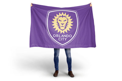 Person holding a purple Orlando City flag with a lion emblem on a white background