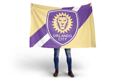 Person holding a Orlando City soccer team flag with a lion emblem on a white background