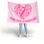 A person holding up a large pink awareness blanket or tapestry with a heart-shaped pink ribbon and heart pattern and the text 'PINK FOR A PURPOSE' on a white studio background. Breast Cancer Flag.