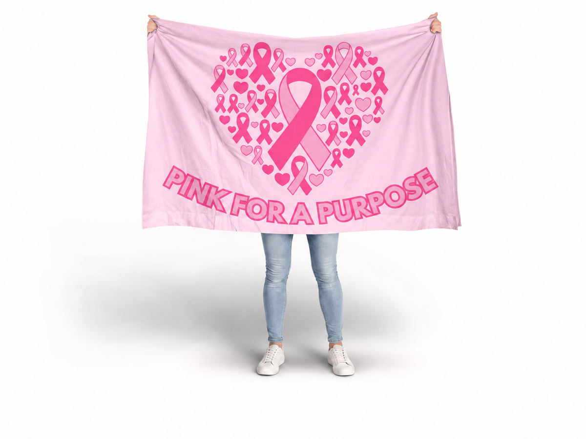 A person holding up a large pink awareness blanket or tapestry with a heart-shaped pink ribbon and heart pattern and the text 'PINK FOR A PURPOSE' on a white studio background. Breast Cancer Flag.