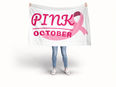 A person standing against a white studio background holding up a large white banner with pink text reading 'PINK OCTOBER' and a pink ribbon graphic. Breast Cancer Flag banner.