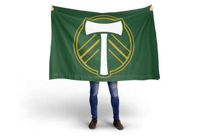 Person holding a green flag with a logo on a white background. Portland Timbers FC Flag.
