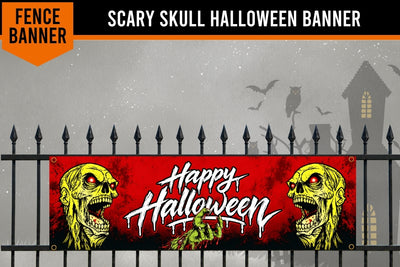 A Halloween-themed fence banner featuring two yellow zombie faces on the sides and white dripping text reading 'Happy Halloween' on a red background, shown hanging in front of a black metal fence with a spooky house and bats in the background.