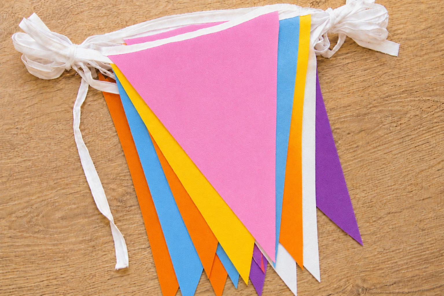 Colorful polyester bunting flags on a wooden surface