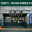Tickets booth with a blue feather banner labeled 'Tickets' in front of a building.