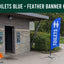 Blue feather banner with 'TOILETS' text in front of a park's toilet, with 'men and woman' image.