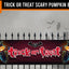 A Halloween-themed fence banner displayed on a black metal fence, featuring the words 'TRICK OR TREAT' in dripping red letters with jack-o'-lantern faces on both sides. The banner is shown against a spooky gray background with silhouettes of a haunted house, bats, and an owl.