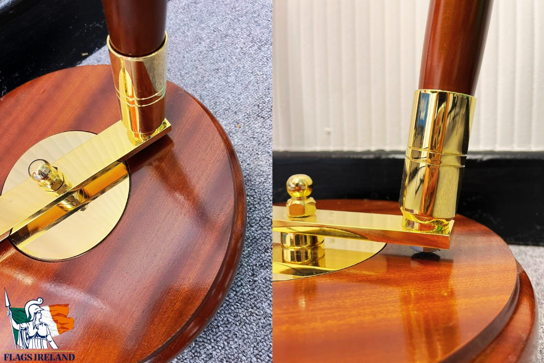 Close-up of a polished wooden flagpole base with a shiny gold metal flag mount and a dark reddish-brown wooden pole, shown in a split view with a small 'Flags Ireland' logo in the corner.