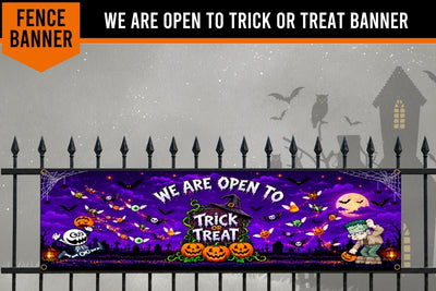 A Halloween-themed fence banner displayed on a black metal fence, featuring a purple spooky sky with bats, ghosts, pumpkins, and the text 'WE ARE OPEN TO TRICK OR TREAT BANNER'.