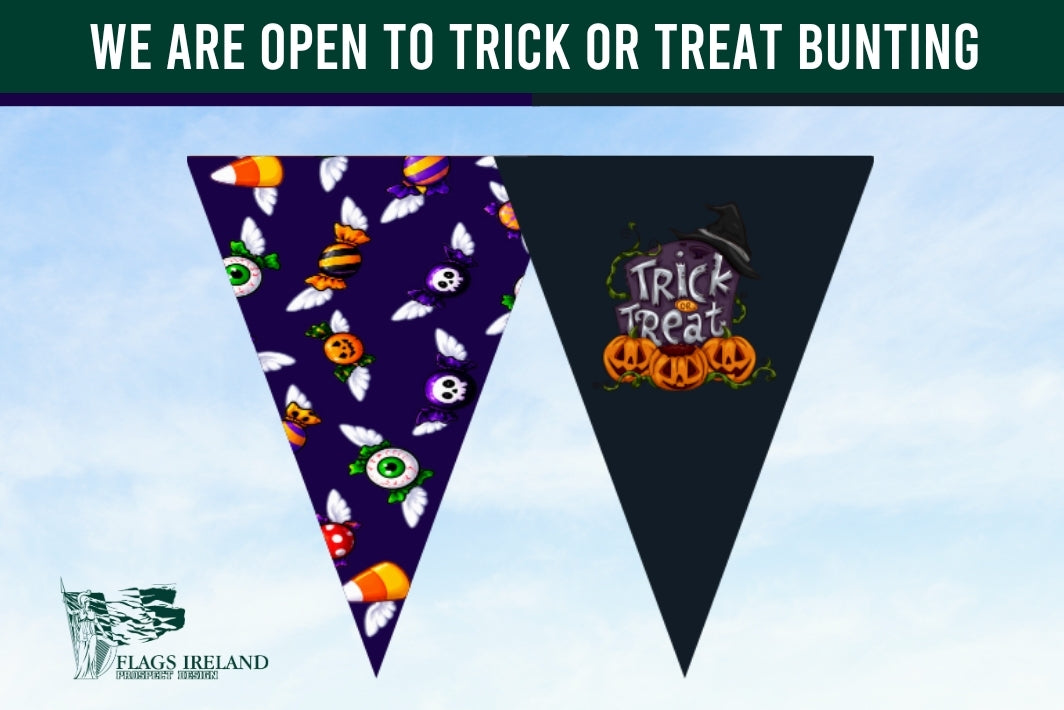 Halloween-themed triangular pennant banner flags with a purple patterned flag featuring bats, skulls, and candy corn, and a dark navy flag with a 'Trick or Treat' pumpkin graphic. A dark green banner at the top reads 'WE ARE OPEN TO TRICK OR TREAT BUNTING' with the 'Flags Ireland' logo in the bottom left on a light blue sky background.